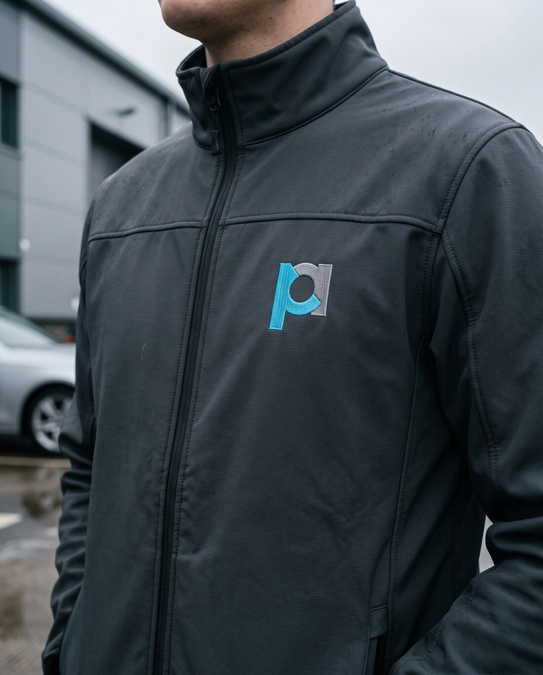 A charcoal softshell jacket with the pa mark embroidered on the chest
